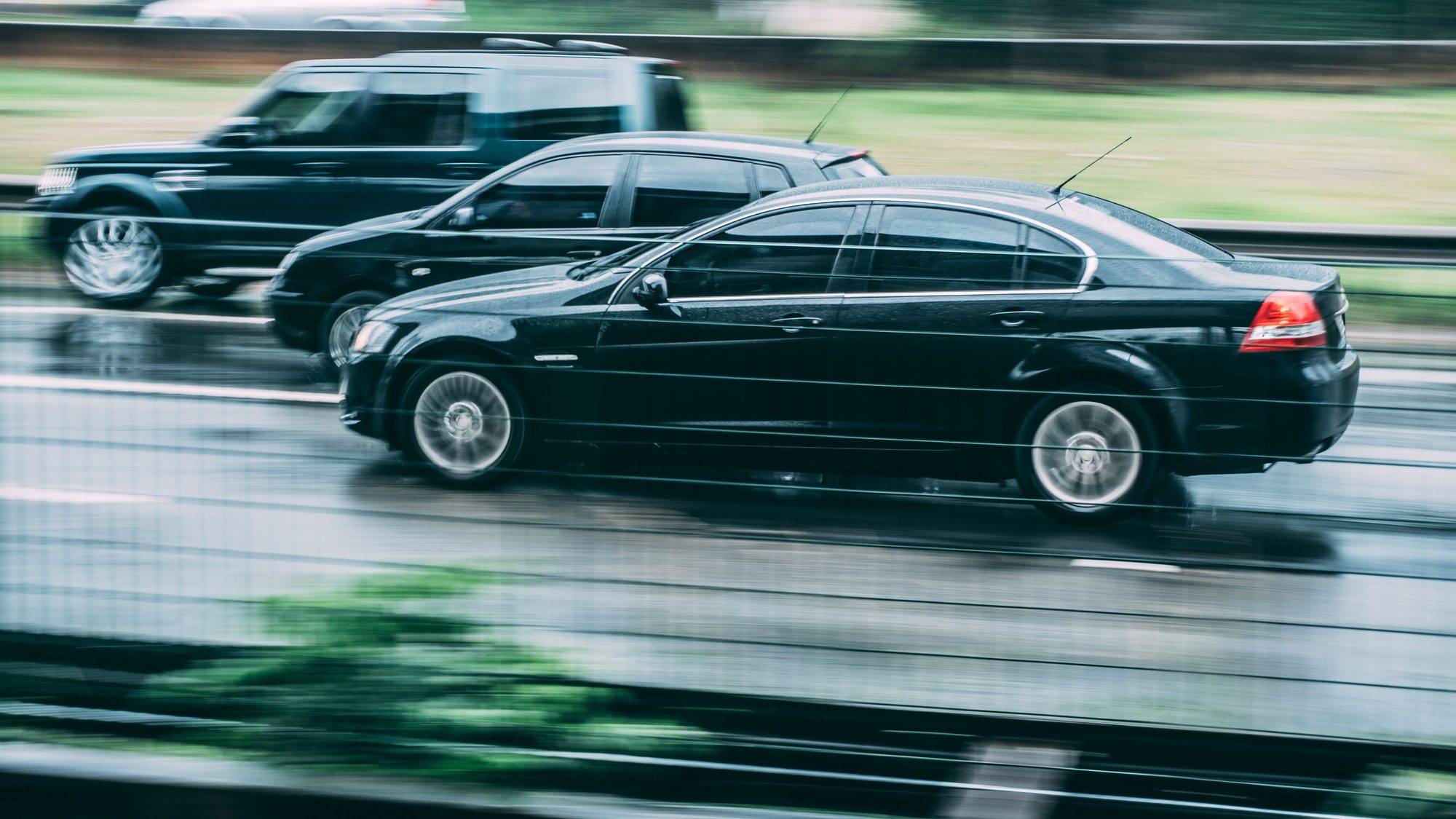 Vehicles in motion on a rain-slicked road, captured with motion blur to convey speed.